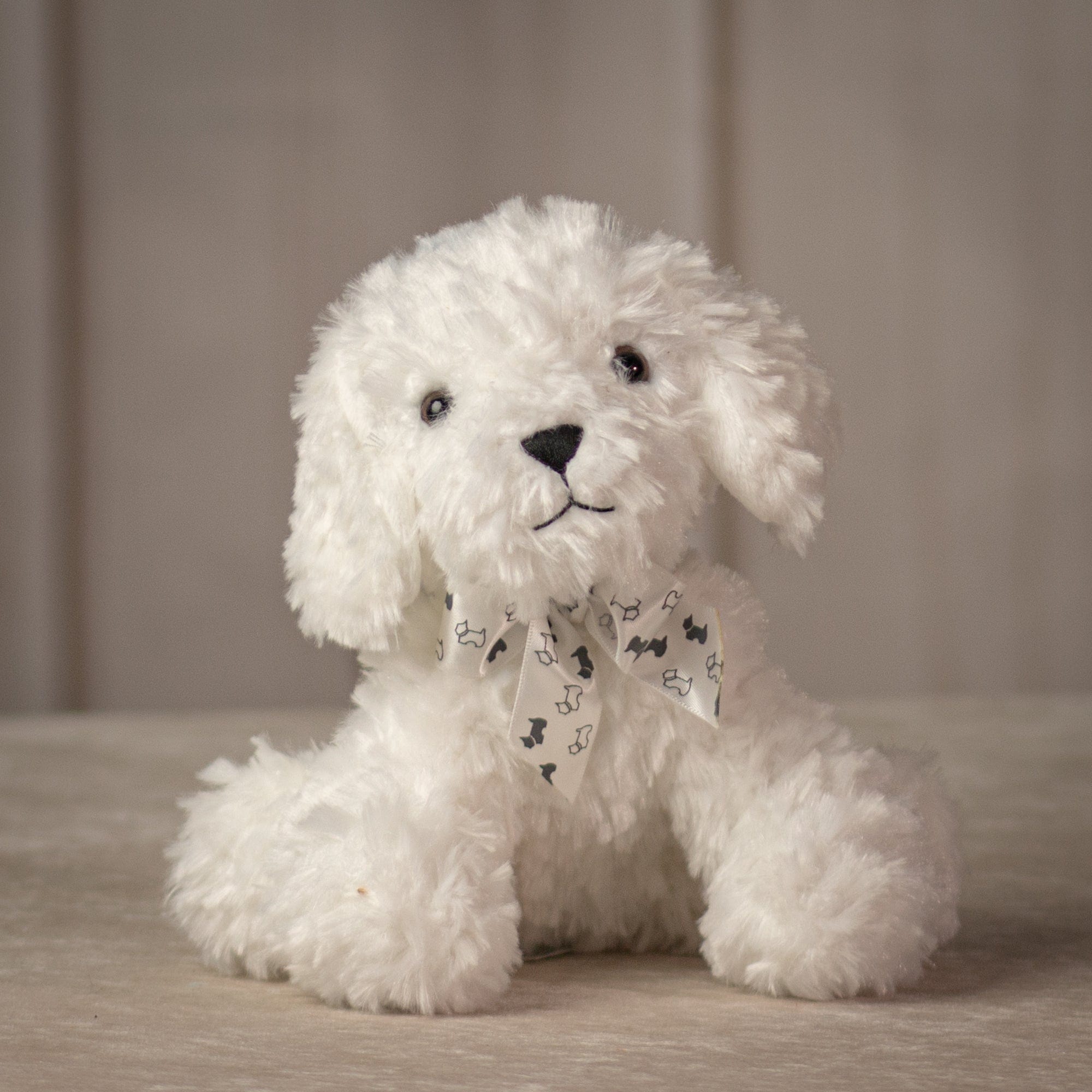 Small sitting white dog with white bow