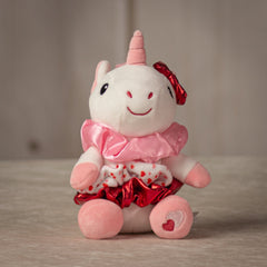 6" stuffed white unicorn keychain with three Valentine's designed hair scrunchies tied around its body