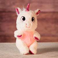 stuffed white unicorn removed from its swaddle with a pink metallic horn