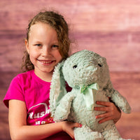 girl holding 16" stuffed green bunny wearing a bow
