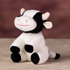 A sitting black and white cow that is 5 inches tall while sitting