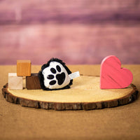 A black paw print that is 4 inches tall from top to bottom on top of a piece of wood