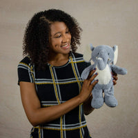 A woman holds a gray elephant that is 13 inches tall while standing