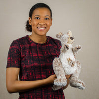 A woman holding a beige kangaroo that is 14 inches tall while standing with a little joey inside