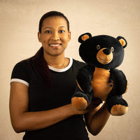 A woman holds a black bear that is 12 inches tall while sitting