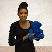 A woman holds a blue bear that is 9 inches tall while sitting