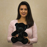 A woman holds a black bear that is 9 inches tall while sitting