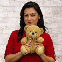 A woman holds a beige bear that is 9 inches tall while sitting