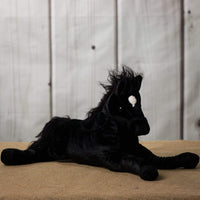 A laying black horse that is 21 inches from head to tail