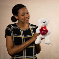 A woman holds a white bear that is 8 inches tall while sitting holding a red Love heart