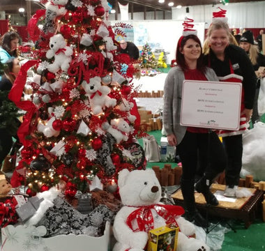 People posing with bear and tree.