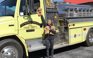 Linda Sheets of Banner Bears holds teddy bears in front of a Spring Creek Fire Department truck during a donation delivery.