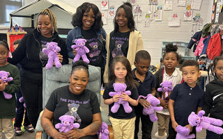 A group of smiling young children holding purple teddy bears in a classroom setting