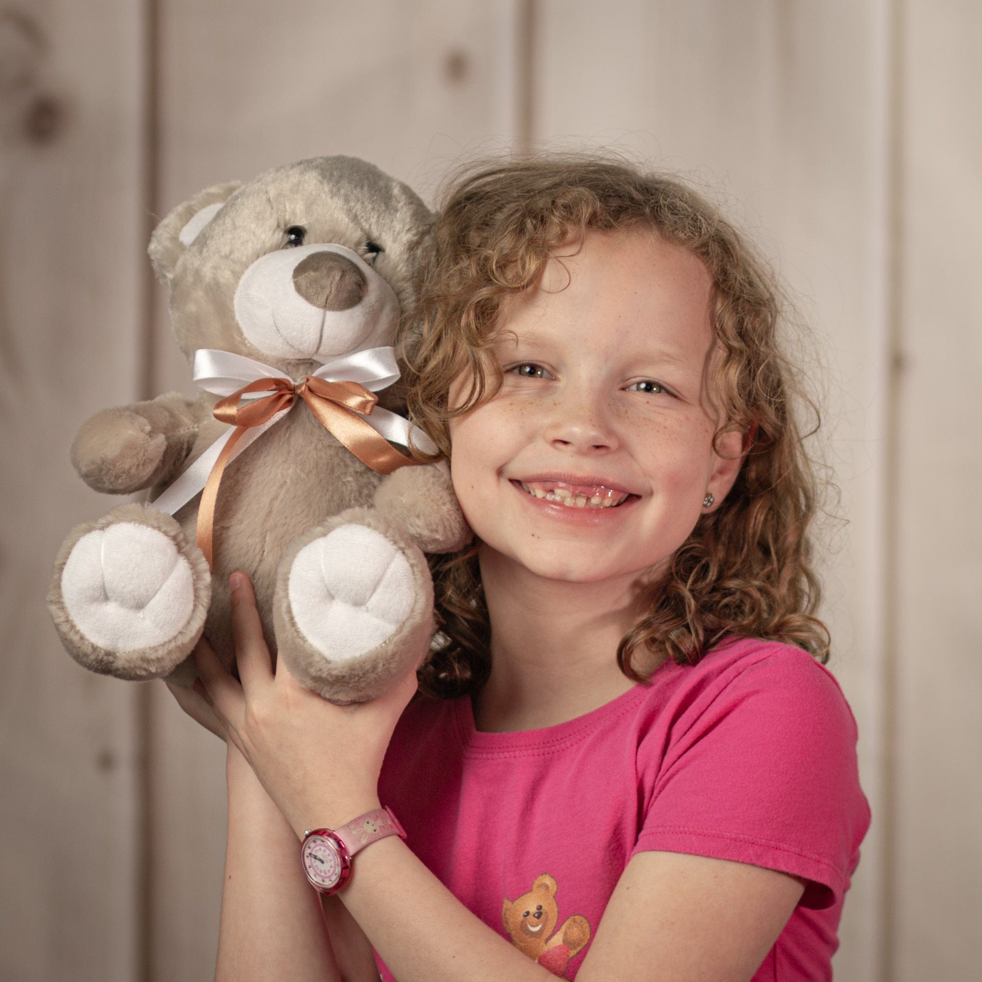Little girl holding 10" grey teddy bear with brown and white bow