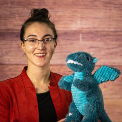 Woman holding a blue plush dragon.