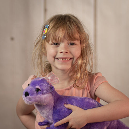 Little girl holding an 18 inch purple otter with a pink polka dotted bow.