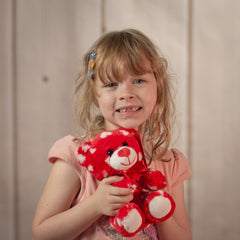 Little girl holding a red 7.5 inch bear covered in white hearts