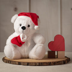 Medium sized white bear wearing a red Santa hat and holding a red stocking