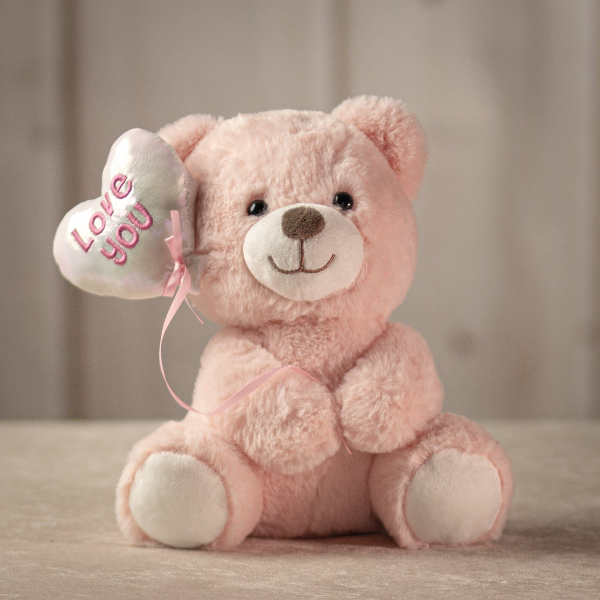 9 inch light pink stuffed bear holding a balloon that says "love you"