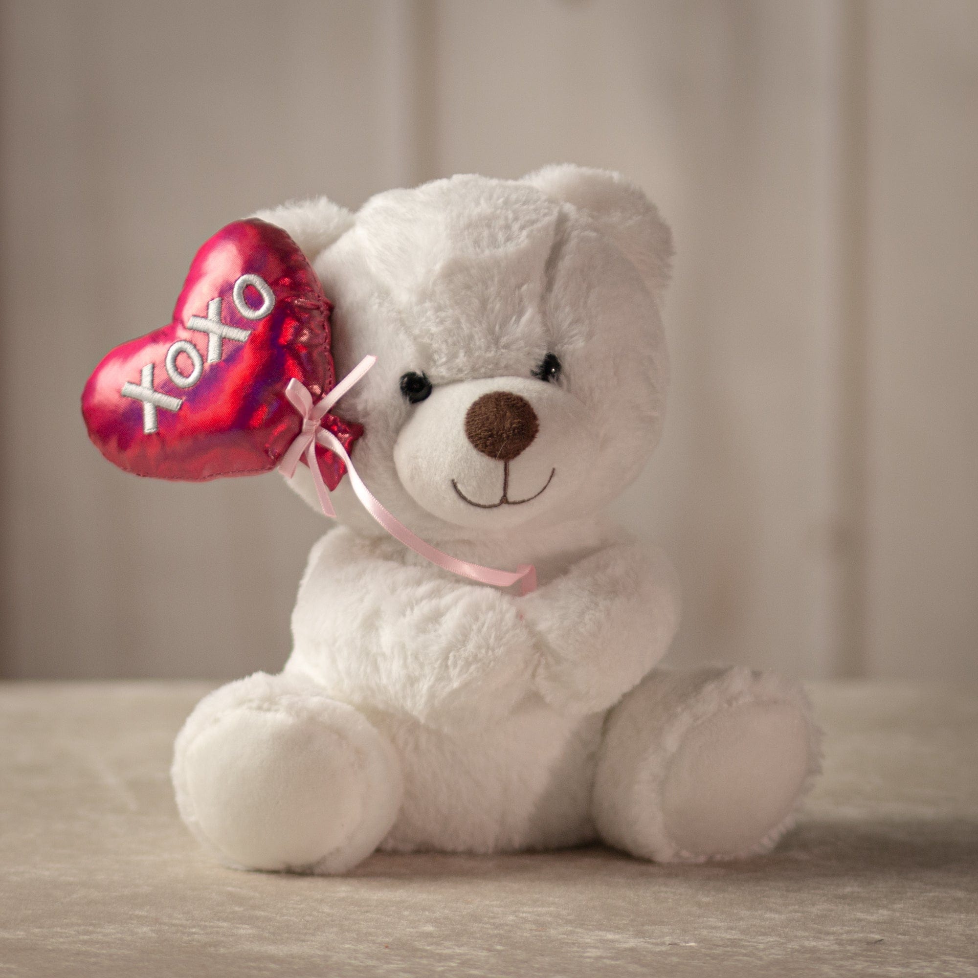 9 inch white stuffed bear holding a balloon that says "xoxo"