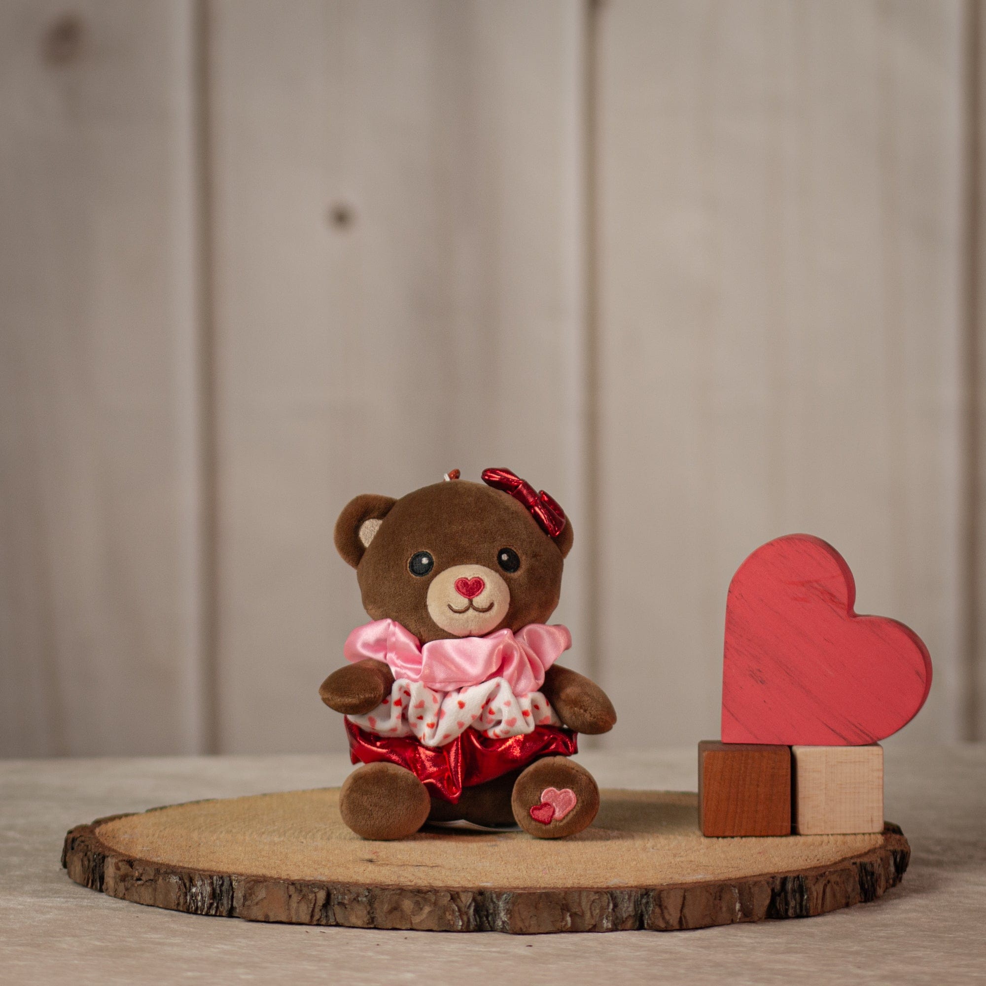 6" stuffed brown bear keychain with three Valentine's designed hair scrunchies tied around its body
