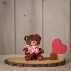 6" stuffed brown bear keychain with three Valentine's designed hair scrunchies tied around its body