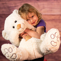 girl holding 18 in cream stuffed bear with paw prints on paws