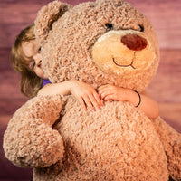 girl holding 37 in brown stuffed large cuddle bear 