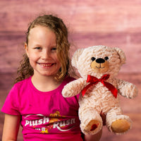 girl holding 12 in two tone tan bear wearing a red bow and has heart on paw