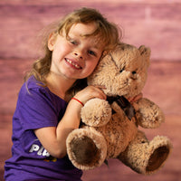 girl holding 10 in brown stuffed teddy bear set wearing a bow