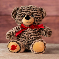 12 in stuffed two tone brown bear wearing a red bow and has heart on paw
