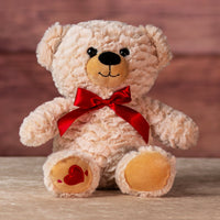 12 in stuffed two tone cream bear wearing a red bow and has heart on paw