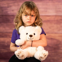 girl holding 10 in stuffed cream bear wearing a bow