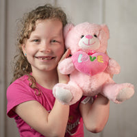 girl holding 9.5" Pastel Valentine Bear Pair in light pink holding a heart that says love and wearing a bow