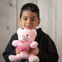 boy holding 9.5" Pastel Valentine Bear Pair in light pink holding a heart that says love and wearing a bow