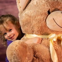 girl holding 36" stuffed bear with bow around neck