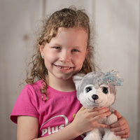 girl holding 10" stuffed grey huskey with eyelashes and blue eyes wearing a bow