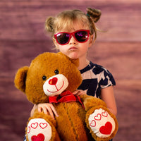 kid holding 14.5 stuffed valentines bear with heart nose and heart paw wearing a bow