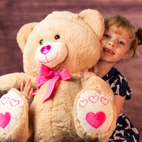 girl holding 19.5 in stuffed valentines day bear with heart nose and paws wearing a bow