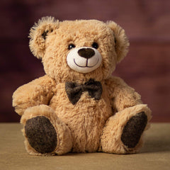 A beige bear that is 10 inches tall while sitting wearing a bowtie that matches his ears and paw prints