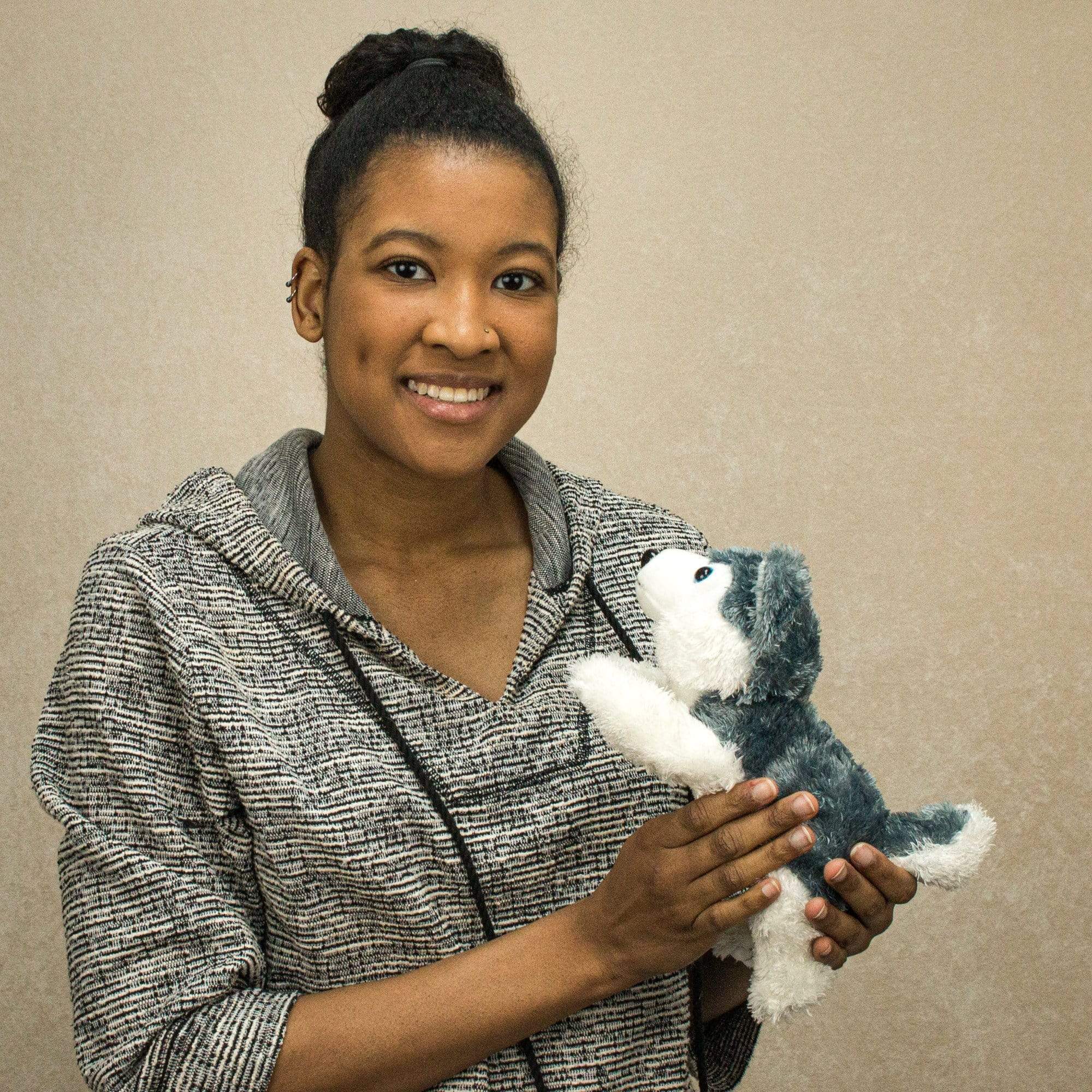 A woman holds a laying grey and white laying husky that is 10 inches from head to tail