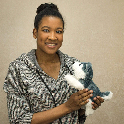 A woman holds a laying grey and white laying husky that is 10 inches from head to tail