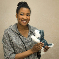 A woman holds a laying grey and white laying husky that is 10 inches from head to tail