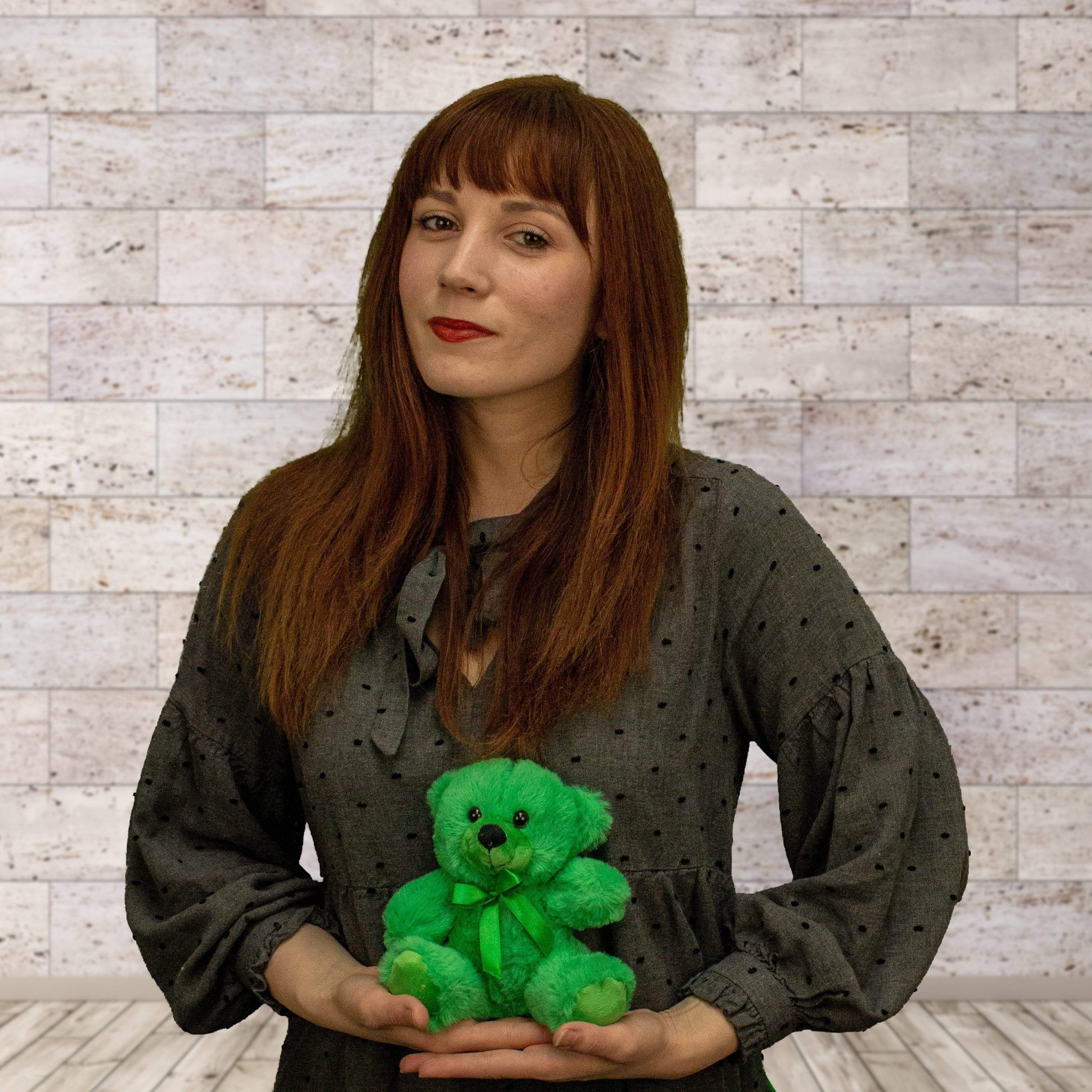 A woman holds a green bear that is 6 inches tall while sitting