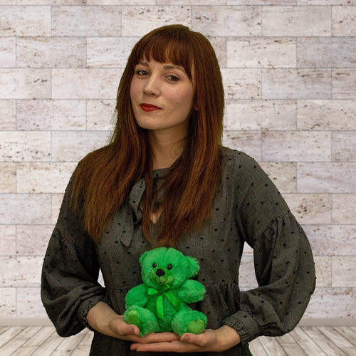 A woman holds a green bear that is 6 inches tall while sitting