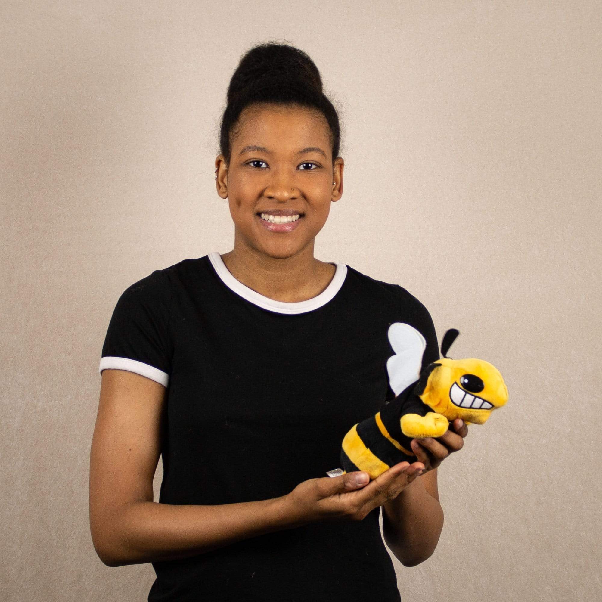 A woman holds a black yellowjacket that is 9 inches from head to tail wearing a black Go Team shirt