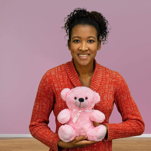 A woman holds a light pink bear that's 9 inches tall while sitting