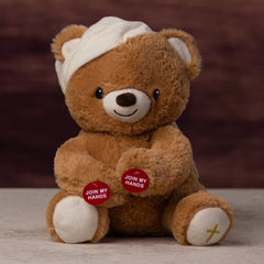 A brown sitting bear that is 9 i8nches tall while sitting wearing a hat and cross on its foot