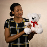 A woman holds a white bear that is 10.5 inches tall while sitting