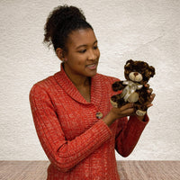 A woman holds a brown bear that is 7 inches tall while sitting